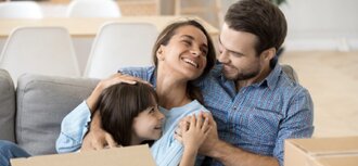 parents with child on sofa surrounded by moving boxes